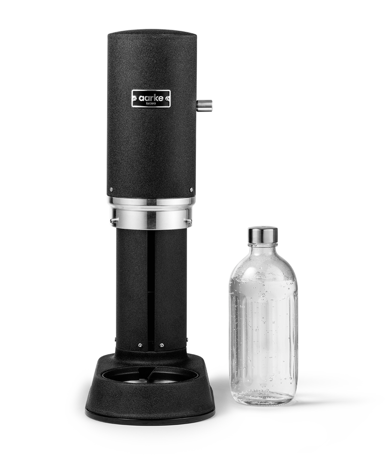 Aarke Carbonator Pro in Matte Black. Front view with chamber open and Glass Bottle sitting beside.